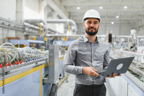 Obraz na plátně Industrial engineer holding laptop, managing production line in factory