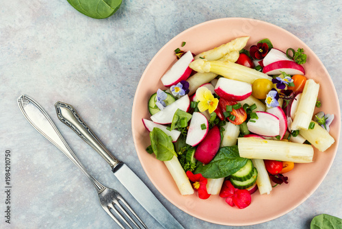 Colorful Vegetable Salad with Asparagus, Radishes and Edible Flowers on a Plate
