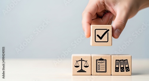 Hand placing a checkmark block on top of legal and compliance icons.