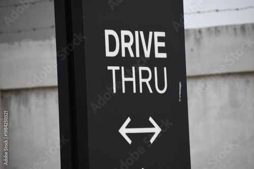 A Drive Thru sign with arrows point on both sides. Black and white sign.