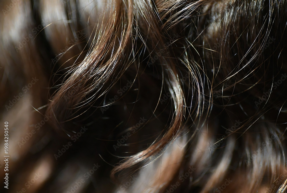 Naklejka premium Subject: Brown hair. Action: Close-up of textured, wavy hair strands. Setting: Dark background.