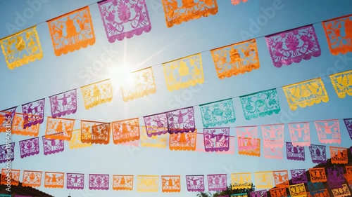 Colorful papel picado banners hanging in blue sky during celebration  