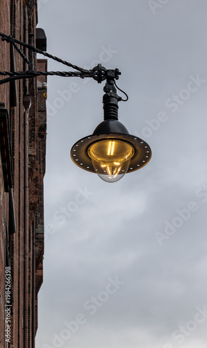 Vintage industrial streetlamp glowing against overcast sky