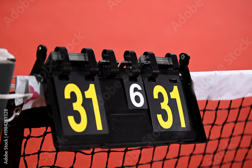 A manual flip-style scoreboard hanging on a net