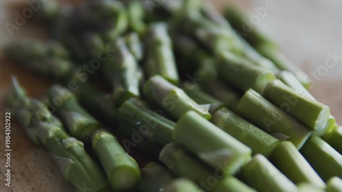Chopped asparagus on wooden board. Healthy food prep, cooking process, green vegetables, clean eating concept, vegan and vegetarian diet.
