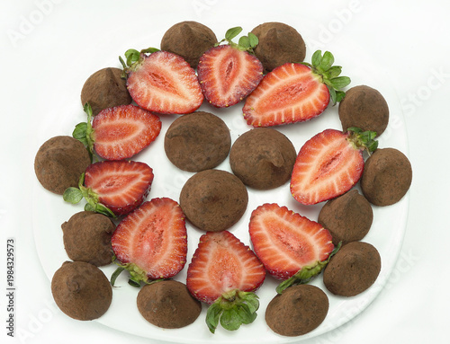 Dessert of red strawberries cut in half with chocolate candies, top view.