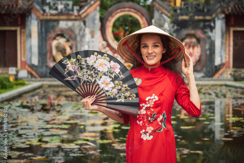 Portrait of a young woman in a red Vietnamese dress in the old district of Hoi An