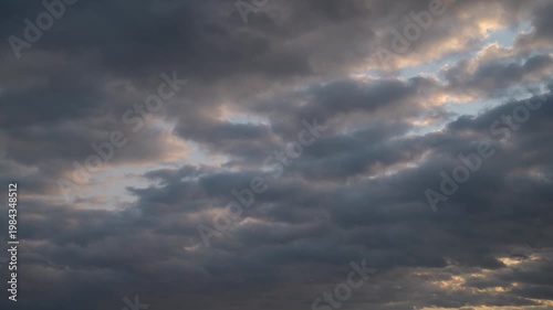 Time-lapse view of dramatic clouds with shifting light effects in the sky.
