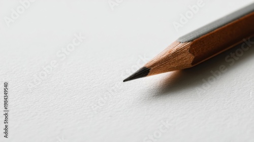 Sharp wooden pencil slants on pure white paper, focused tip with visible grain, soft lighting, clean minimal background.