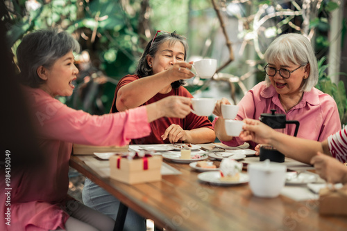 Photos Senior women friends raising coffee cups together at garden cafe table celebrating moment with laughter and conversation
