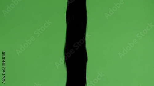 Dynamic black liquid stream pouring down vertically against a vibrant green screen, perfect for compositing effects, visual projects, and creative video content creation