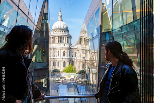 People are viewing the historic st paul's cathedral reflecting in a modern glass building