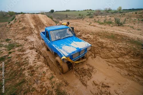 Blue pickup truck driving through deep mud ditch