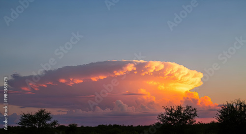 A large cumulonimbus cloud formation at sunset with vibrant colors in the sky