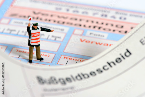 Fotografie Ein Modell-Polizist steht auf einem Bußgeldbescheid und Verwarnungszettel