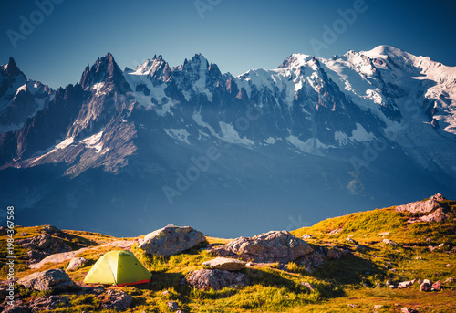 Tourist tent on a slope among snow-capped mountains that tower majestically in the distance. Location place Mont Blanc massif, Chamonix, France, Europe.