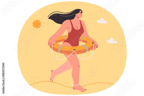 Woman beach lifeguard dressed in swimsuit walks along seashore with lifebuoy on belt