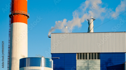 the chimney and buildings of a thermal power plant against the blue sky