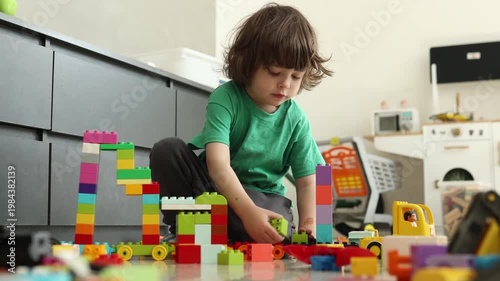 Young boy playing with colorful building blocks on the floor at home, focused on creative play and learning.