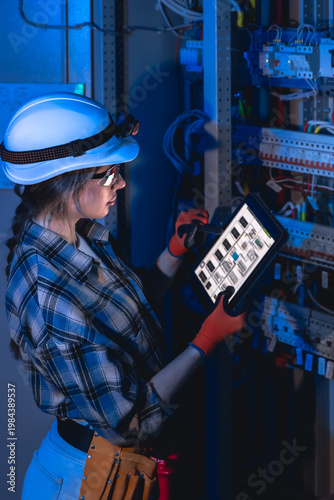 Female engineer managing electrical system with tablet near switchboard. Electrical inspection.