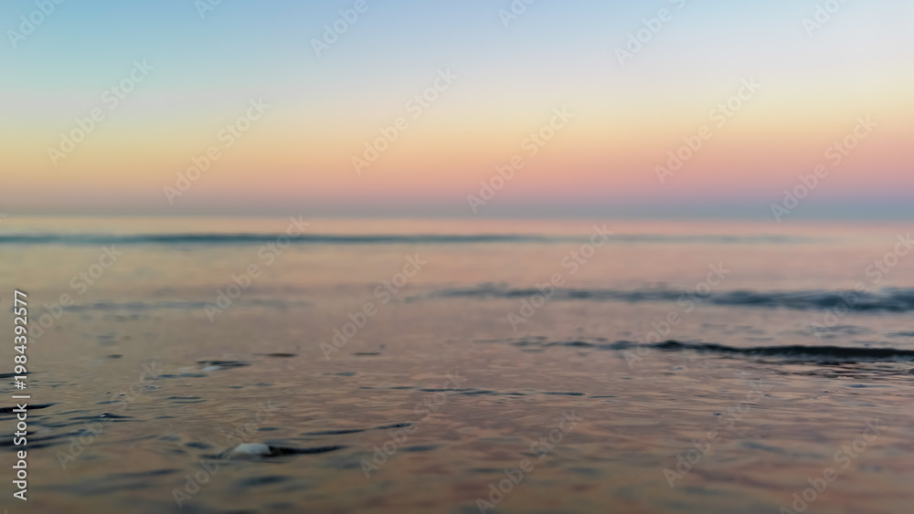 Fototapeta premium Macro shot of water on the beach during twilight. Focus on wet sand texture.