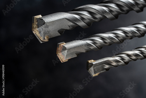 Professional masonry drill bits, closeup. Three SDS plus drill bits for concrete and brick, showing carbide tips and spiral texture, ideal for construction and industrial tool marketing