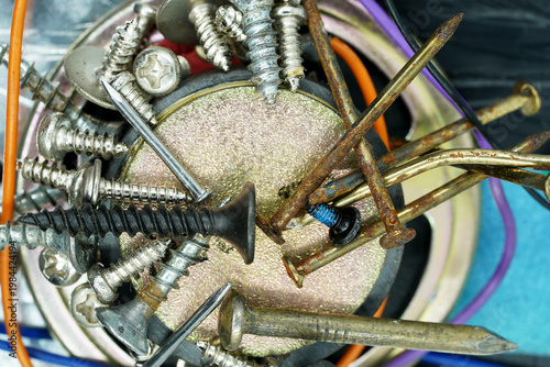 Macro Shot of Rusty Nails and Various Screws Stuck to a Round Magnet on Industrial Surface