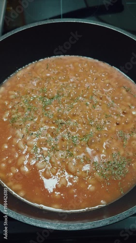Cooking beans in tomato sauce. Canned beans. The process of cooking beans, stirring, and adding spices.	
