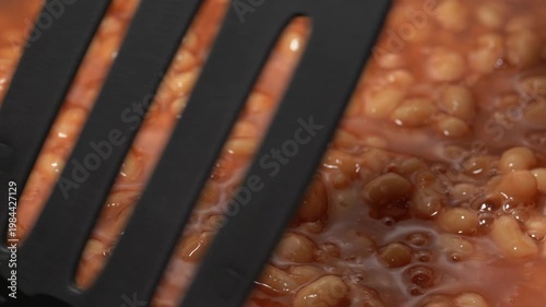 Cooking beans in tomato sauce. Canned beans. The process of cooking beans, stirring, and adding spices.	
