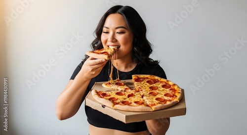 Woman enjoying a slice of pizza from a box against a neutral background