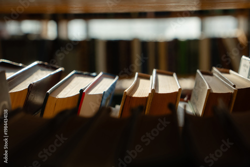 Fotografie Old books on the bookshelf in library archive interior in sunny day