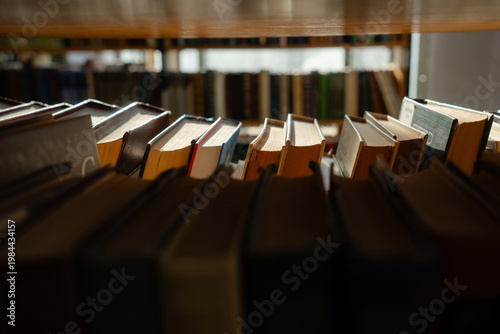 Old books on the bookshelf in library archive interior in sunny day. Shallow depth of field