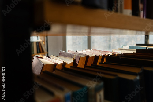 Old books on the bookshelf in library archive interior in sunny day. Shallow depth of field