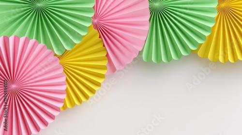 Colorful paper fans in pink, green and yellow radiate against a plain white background, festive decoration.