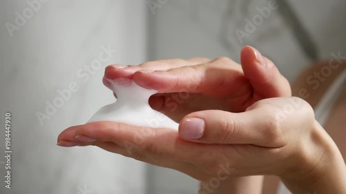 Close-up of young woman demonstrating foam texture for face cleansing.