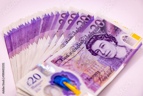 A stack of twenty pound banknotes from the Bank of England featuring Queen Elizabeth II, isolated on white background