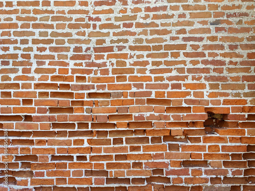 Renovated red brick wall with pothole and signs of wear and tear. Repair of old buildings. Urban background. Full frame.