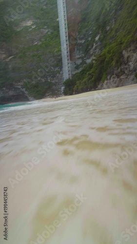 Beautiful ocean waves hitting the shore at Kelingking Beach on Nusa Penida, Bali, creating a cinematic tropical seascape.