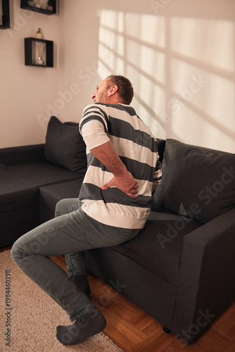 Man with hip, back, spine and sciatica pain at home.