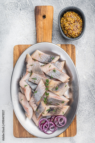 Obraz na płótnie Marinated salted herring fish pieces with mustard and thyme in white plate