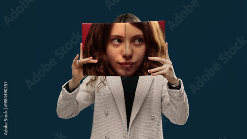 Bilde på lerret Young woman holding printed face panel aligning with real face studio portrait