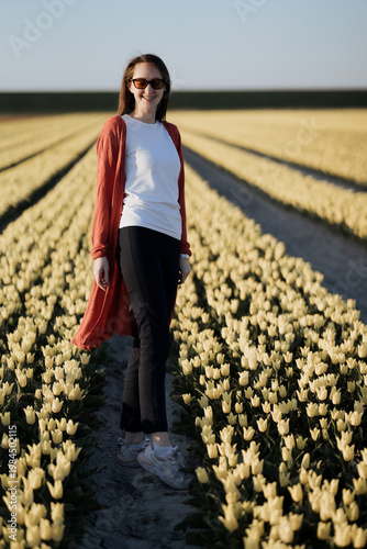 Beautiful Woman standing in colorful tulip flower fields in Amsterdam region, Holland, Netherlands. Magical Netherlands landscape with tulip field in Holland Trevel and spring concept