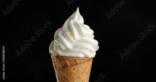 Vanilla ice cream in a waffle cone close-up on a turntable. Close-up footage on a black background.
