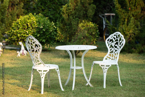 White metal table and chairs in garden with morning light