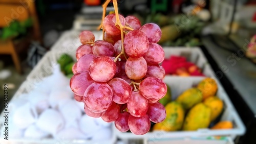 Fotografía Plump red grapes hang in a market display