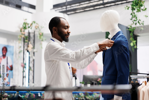 Billede på lærred Clothes retail shop african american assistant dressing mannequing in formal suit to showcase apparel in stock