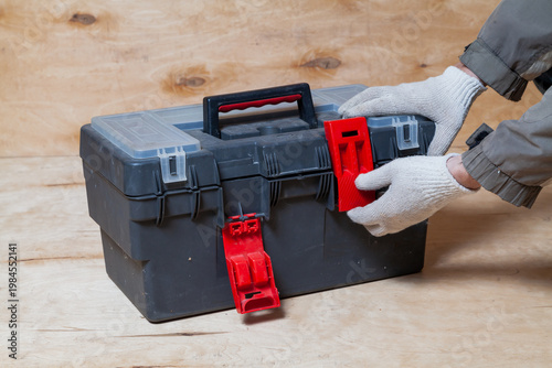 Hands open toolbox on wooden background