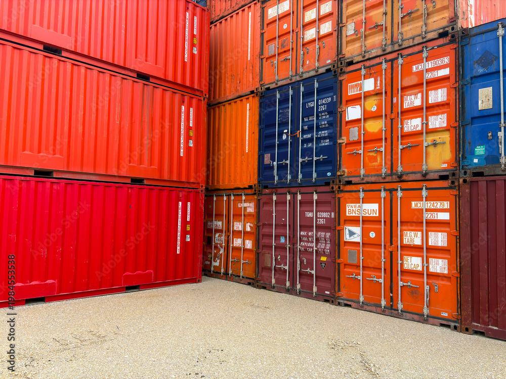Fototapeta premium Stacked blue and red industrial shipping containers in a freight terminal.