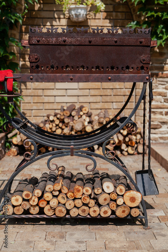 Forged brazier with firewood stands in yard