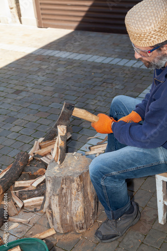 Man with glasses chopping wood in courtyard of house